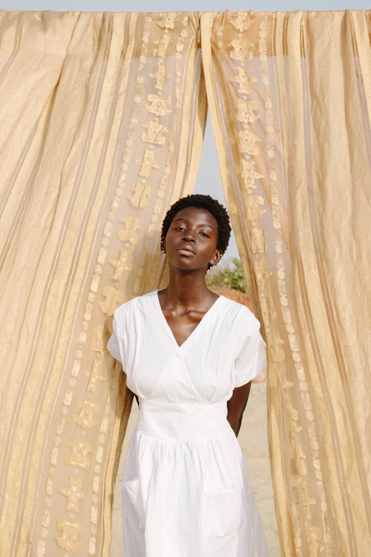 Woman Posing In Dress Between Curtains