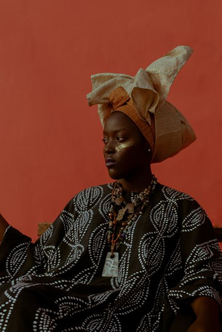 Striking portrait of a woman in traditional attire with a red background, showcasing cultural beauty.