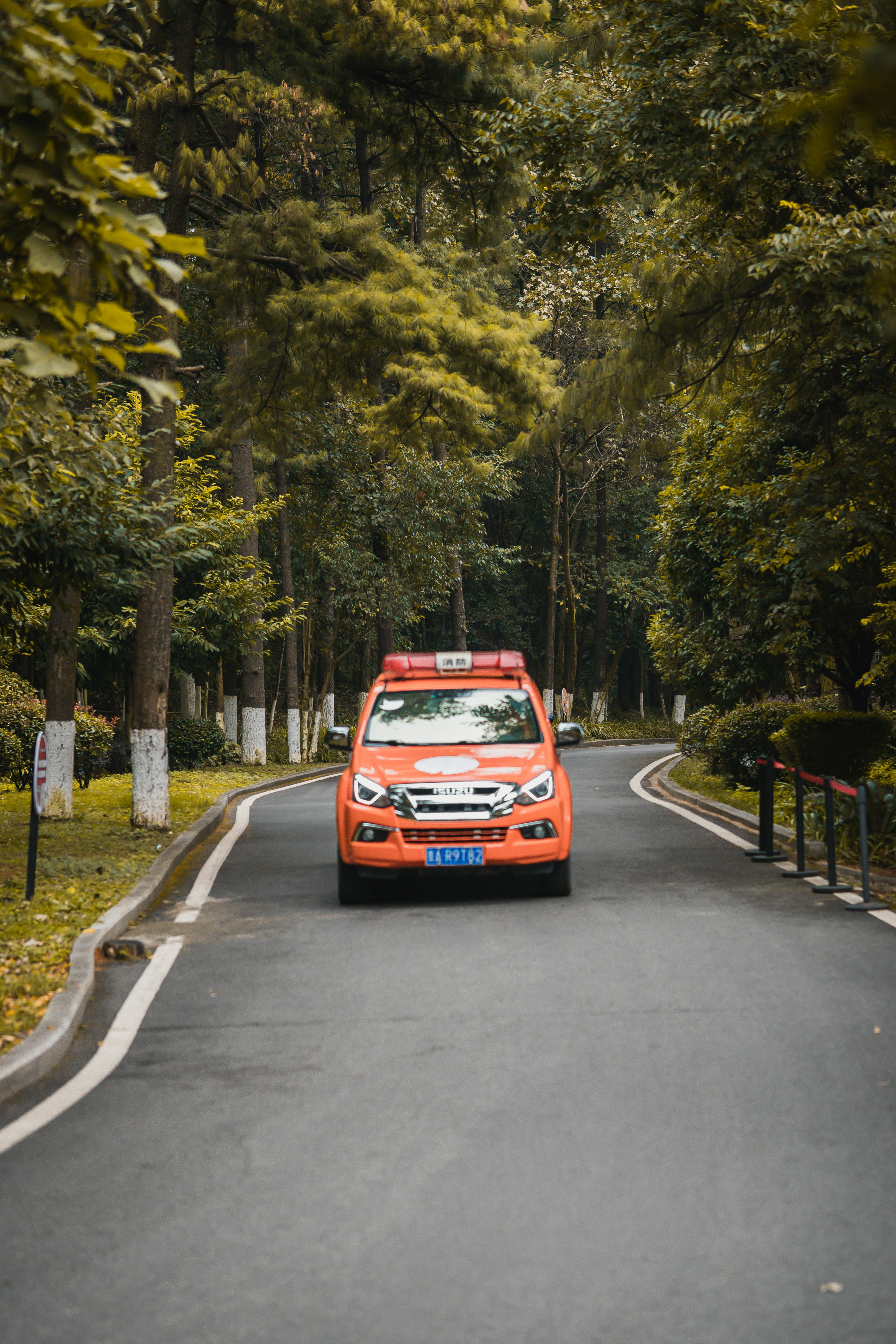 Orange Police Car Driving on Asphalt Road · Free Stock Photo