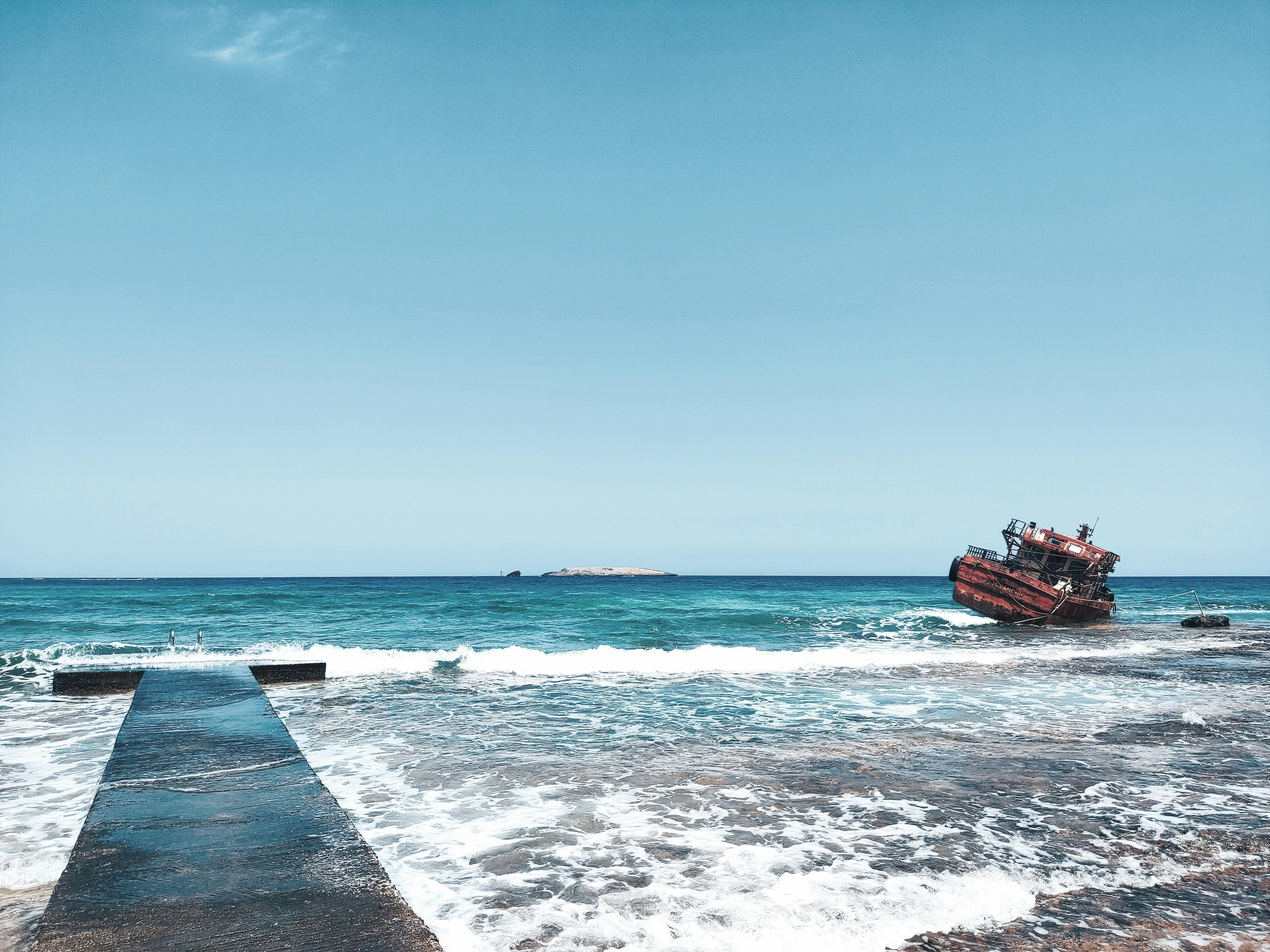 Red and Black Boat on Ocean under Blue Sky · Free Stock Photo