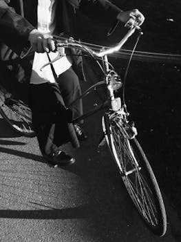 Artistic black and white photo of person cycling on a vintage bicycle, highlighting the simplicity of city commuting.