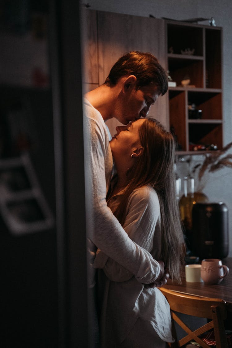 Man Kissing A Woman On Her Forehead