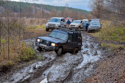 Off-road vehicles navigating a challenging muddy terrain in the countryside forest.
