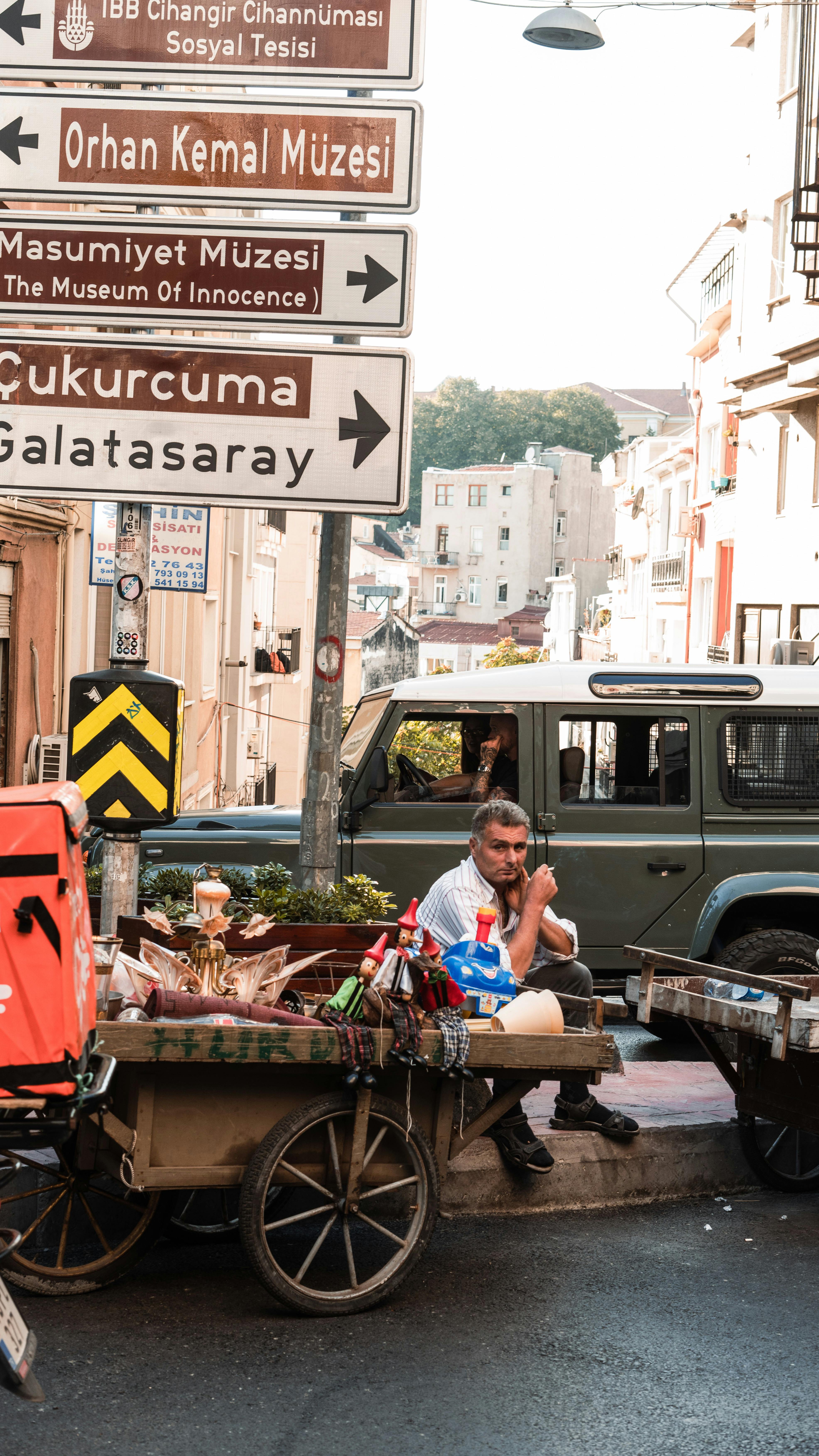 Street vendor selling goods in a busy urban district with iconic museum signs in the background.