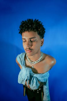 Stylish portrait of a young man with fashion accessories against a blue backdrop.