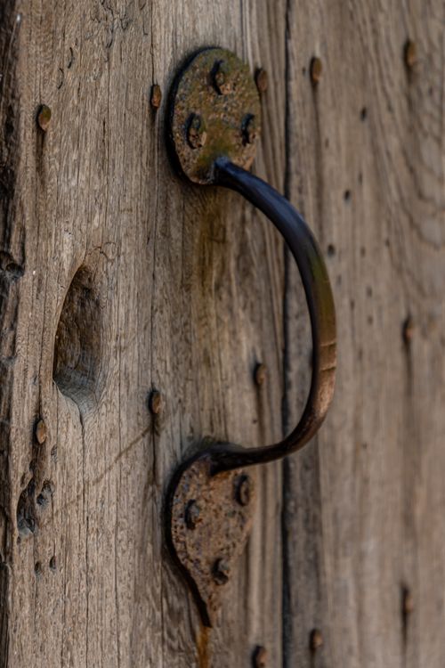 Free Close-up of a vintage brass door handle on a weathered wooden door with selective focus. Stock Photo