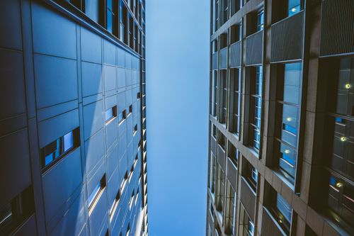 Free Low angle view of modern urban buildings against a clear blue sky, highlighting architectural symmetry. Stock Photo