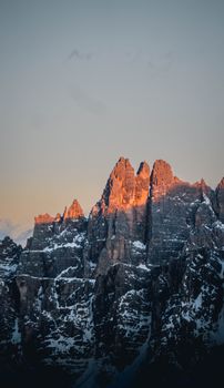 A breathtaking view of snowy mountain peaks in the Dolomites during sunset, with a warm glow.