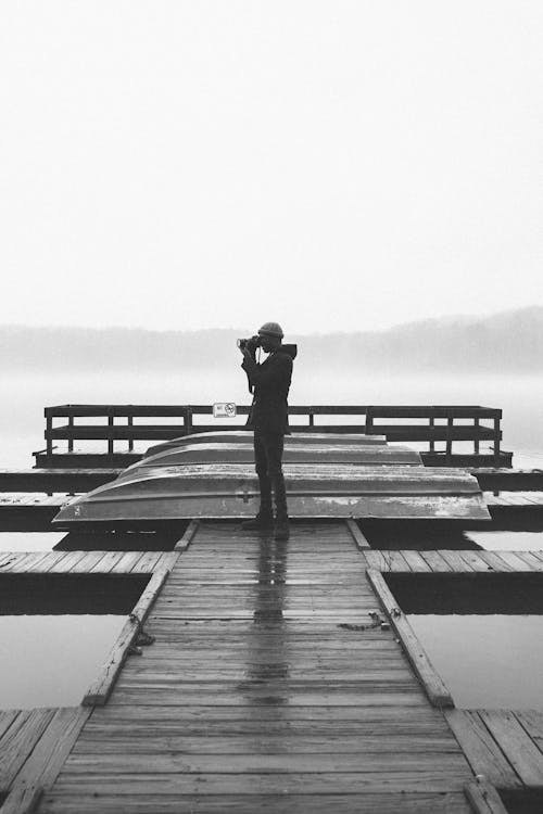 Free Grayscale Photo of a Photographer on a Wooden Dock Stock Photo