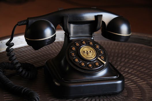 Close-up of a classic black vintage rotary dial telephone on a textured table.