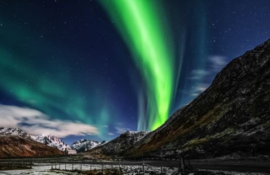 Captivating aurora borealis illuminating snowy mountains at night.