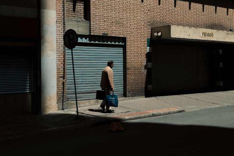 A Person With Bags Walking On A Sidewalk