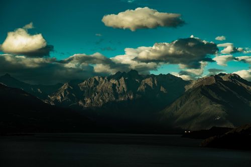 Free A stunning view of a mountain range with dramatic clouds and deep shadows, offering a picturesque landscape. Stock Photo