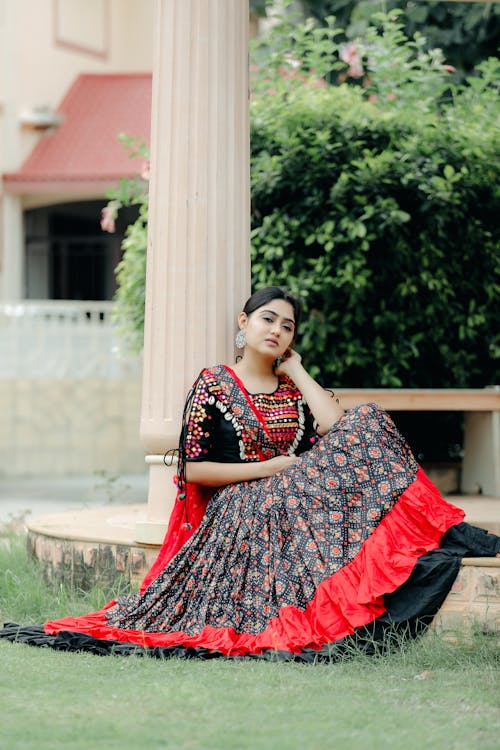 Woman in Traditional Dress Sitting near Column in Garden