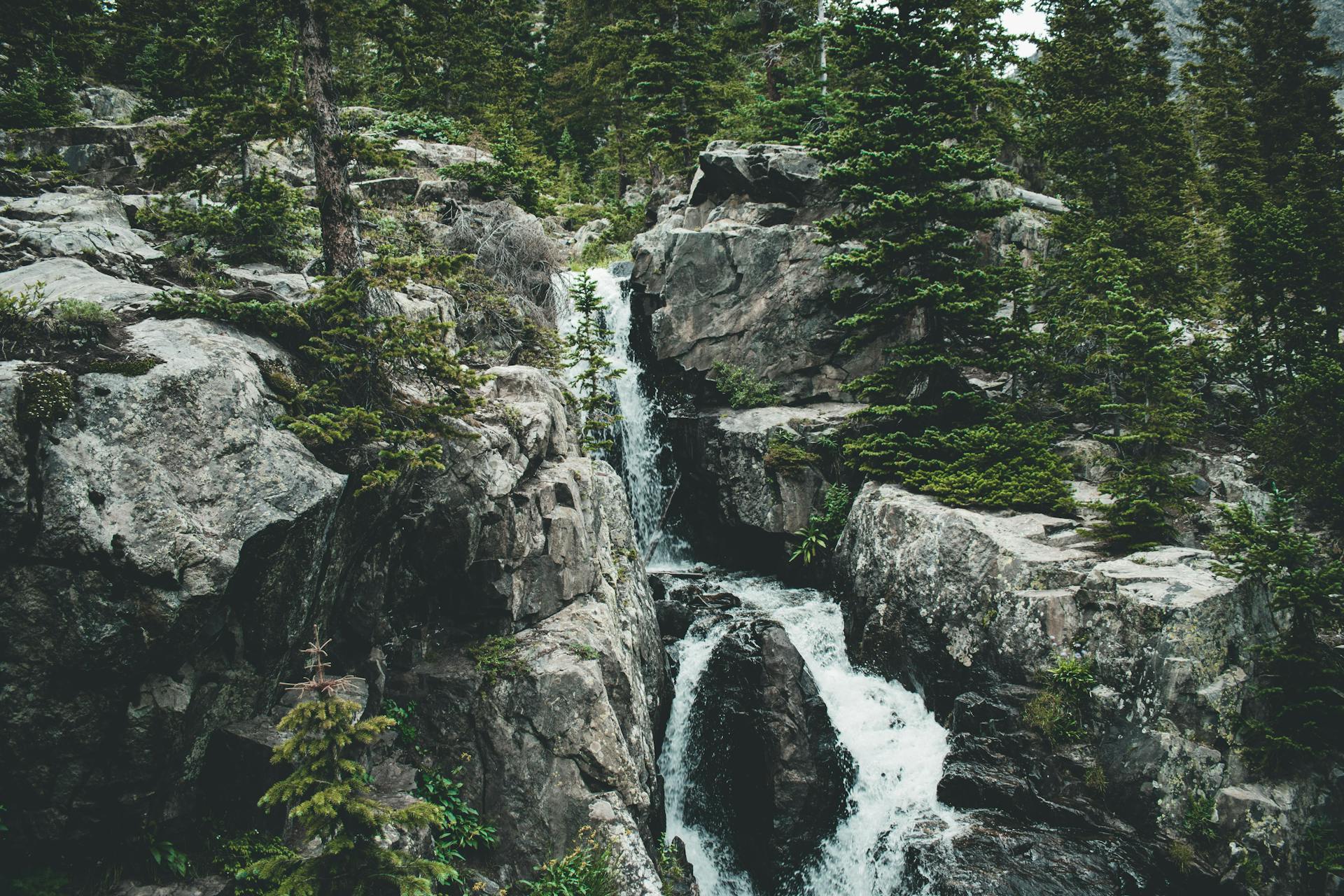 Breathtaking view of a cascading waterfall amidst rugged rocks and lush trees.