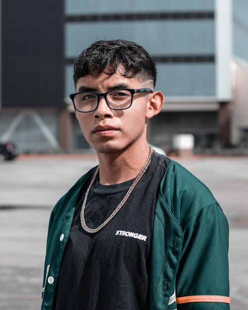 Portrait of a Teenage Boy Standing in Black and Dark Green Button Up Shirt Wearing Eyeglasses