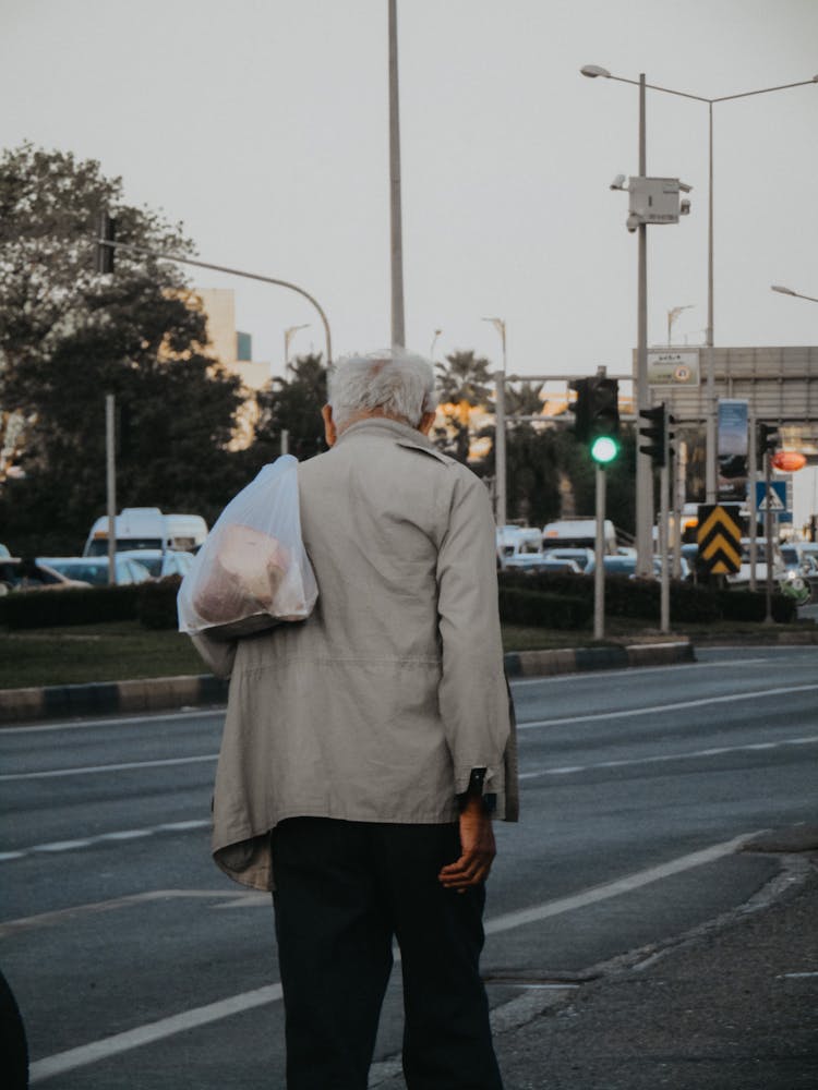 Eldery Man With A Shopping Bag Walking In A City 