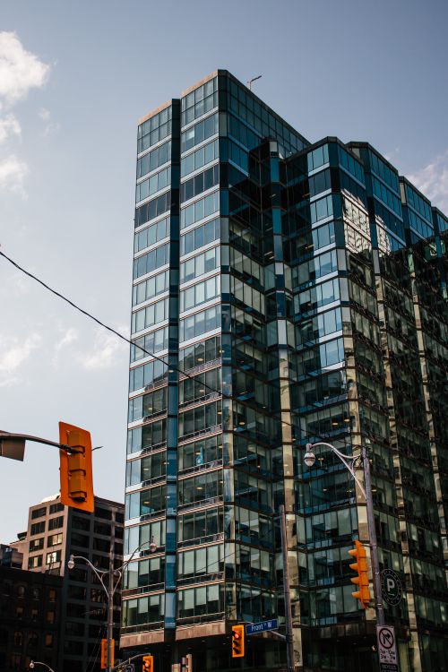 Free Urban scene of a modern glass skyscraper reflecting the sunlight under a clear blue sky. Stock Photo