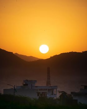 Stunning sunset view over mountains and village silhouette, creating dramatic ambiance.