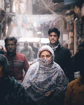 People in warm attire navigate a busy street market on a chilly day.