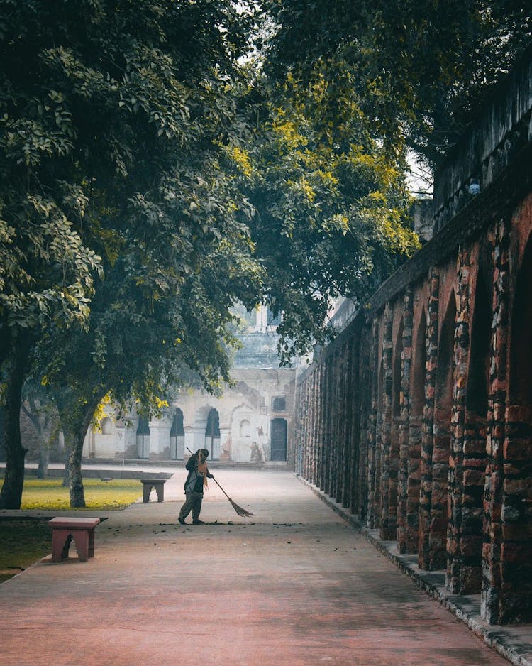 Woman Sweeping Street In Park