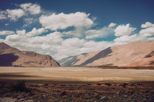 Free Vast desert scene with majestic mountain ranges under a blue sky with clouds. Stock Photo