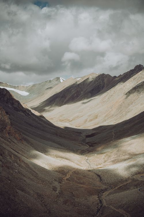 Free A stunning aerial view of a mountain range with dramatic shadows and a cloudy sky. Stock Photo