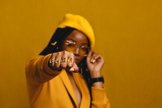Woman Wearing All Yellow Posing with Her Fist Reached Towards the Camera 