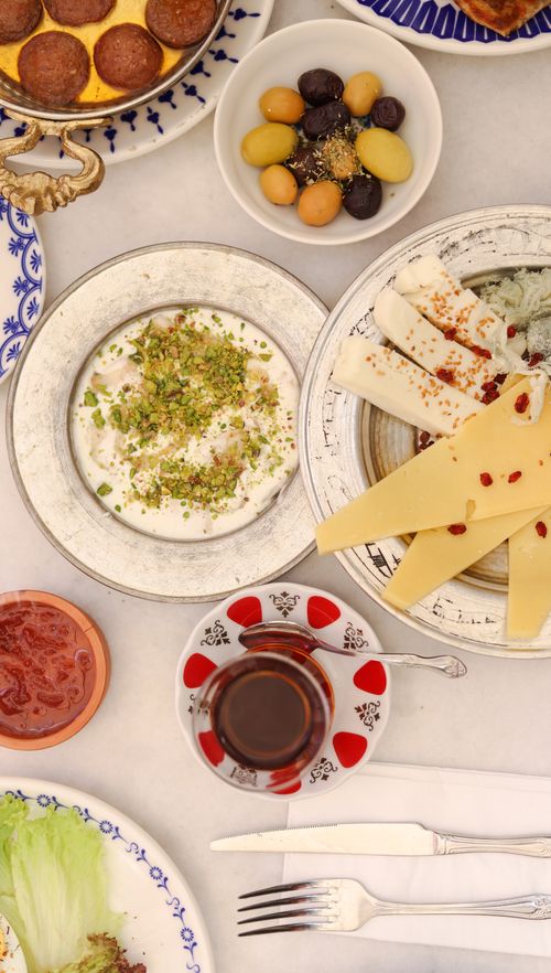Free A delectable spread of Mediterranean breakfast featuring cheese, olives, and tea on a white table. Stock Photo