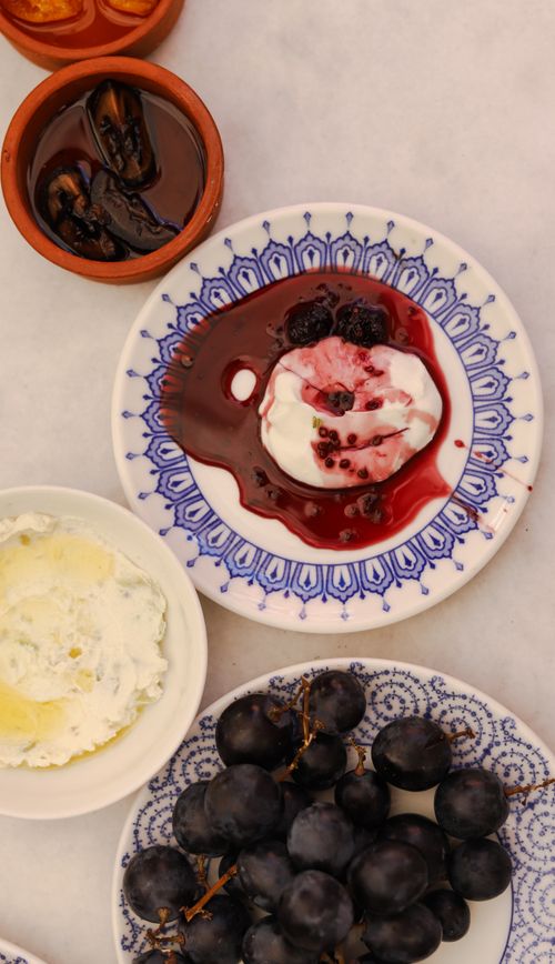 Free A close-up of a dessert plate with cream, berries, and grapes on a decorative dish. Stock Photo