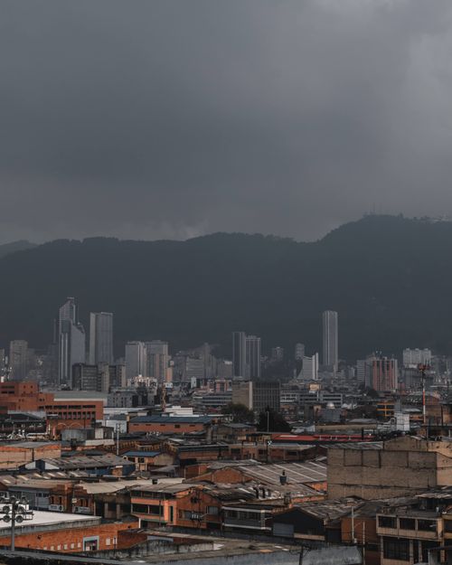 Free A cityscape featuring skyscrapers against the backdrop of misty mountains and stormy skies. Stock Photo