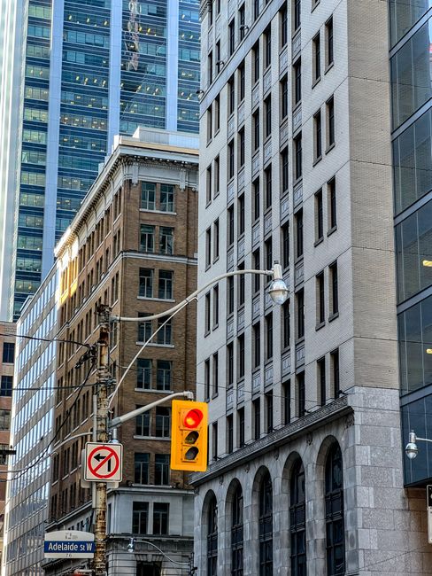 Street view of downtown Toronto with historic and modern buildings and a traffic light.