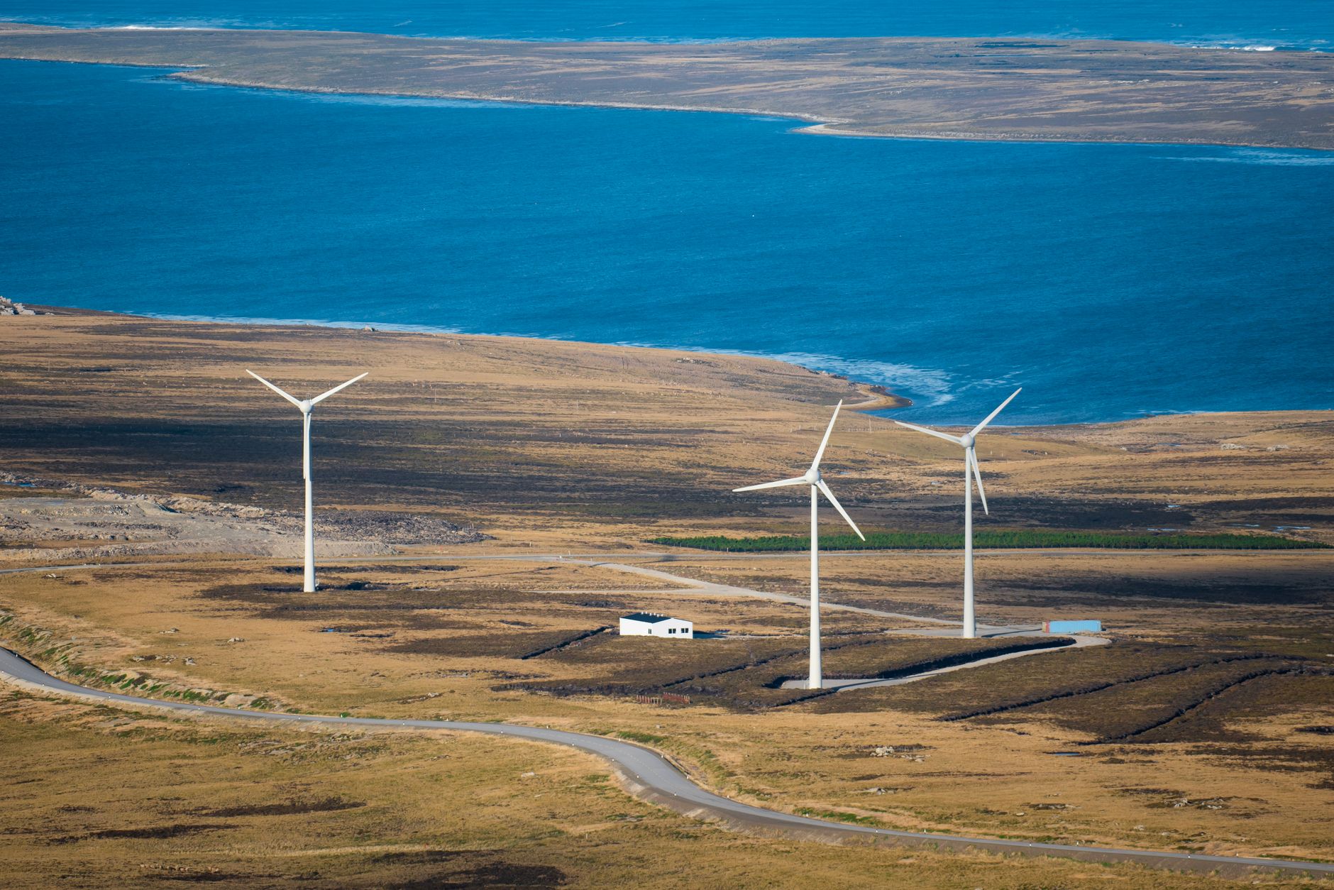 Aerial view of wind turbines on East Falkland near the ocean, showcasing sustainable energy in a natural landscape.