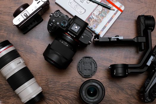 A flat lay of various camera equipment including lenses and cameras on a wooden surface.