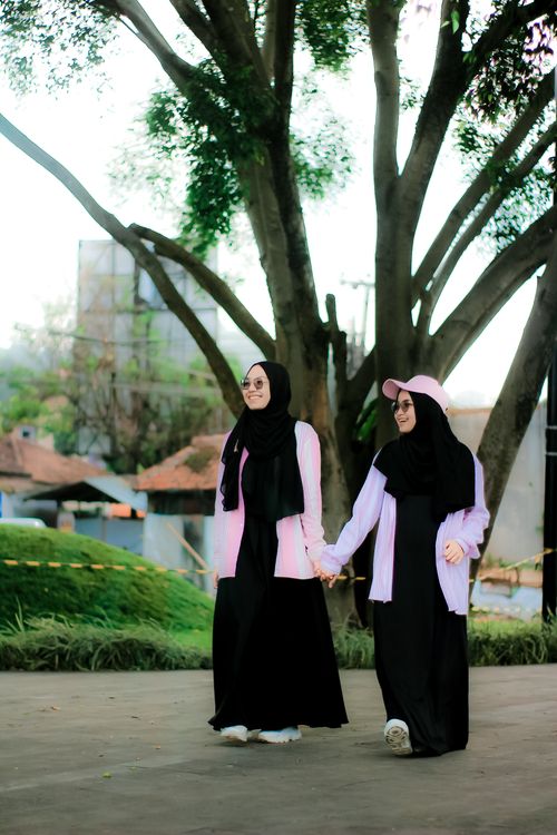 Free Two women in traditional attire enjoying a walk in a park in Jawa Barat, Indonesia. Stock Photo