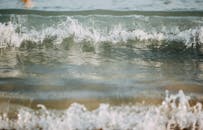 阳光下，温柔的海浪拍打着沙滩，构成一片宁静的景色