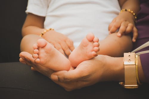 Free Photo of a Person's Hand Holding a Baby's Feet Stock Photo