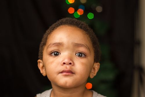 Free Emotional child portrait showing tears and sadness with a blurred festive background. Stock Photo