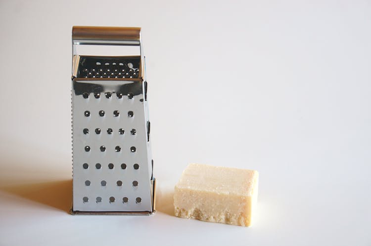 Cheese Beside A Grater On White Surface