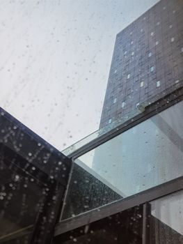 Striking low-angle view of a modern glass skyscraper in Zagreb framed by rain droplets.