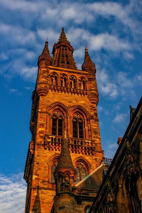 Free Low-angle view of historic University of Glasgow tower against a blue sky at sunset. Stock Photo
