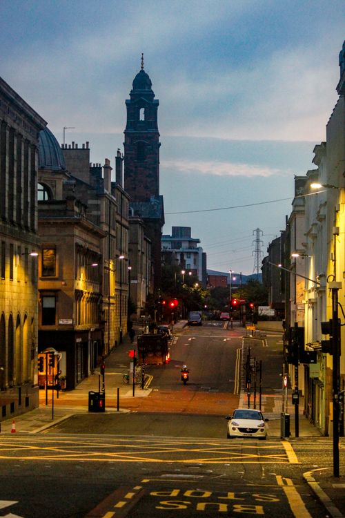 Free Street scene in Glasgow at dusk featuring historic architecture and urban life. Stock Photo