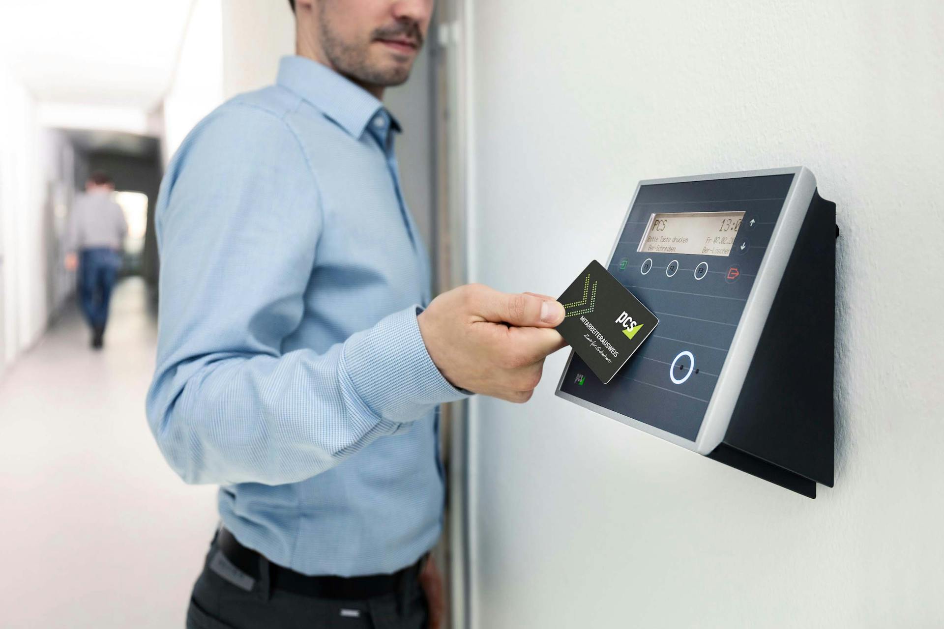 Businessman uses RFID card reader for secure office access, enhancing workplace security.