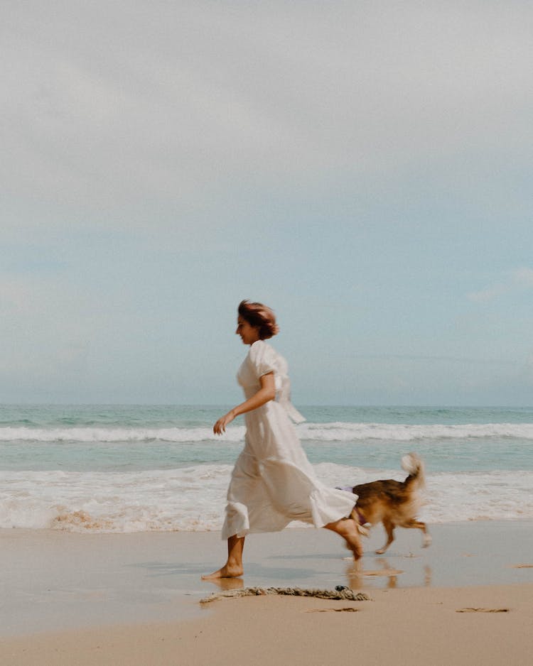 Woman Running With Her Dog On The Beach 