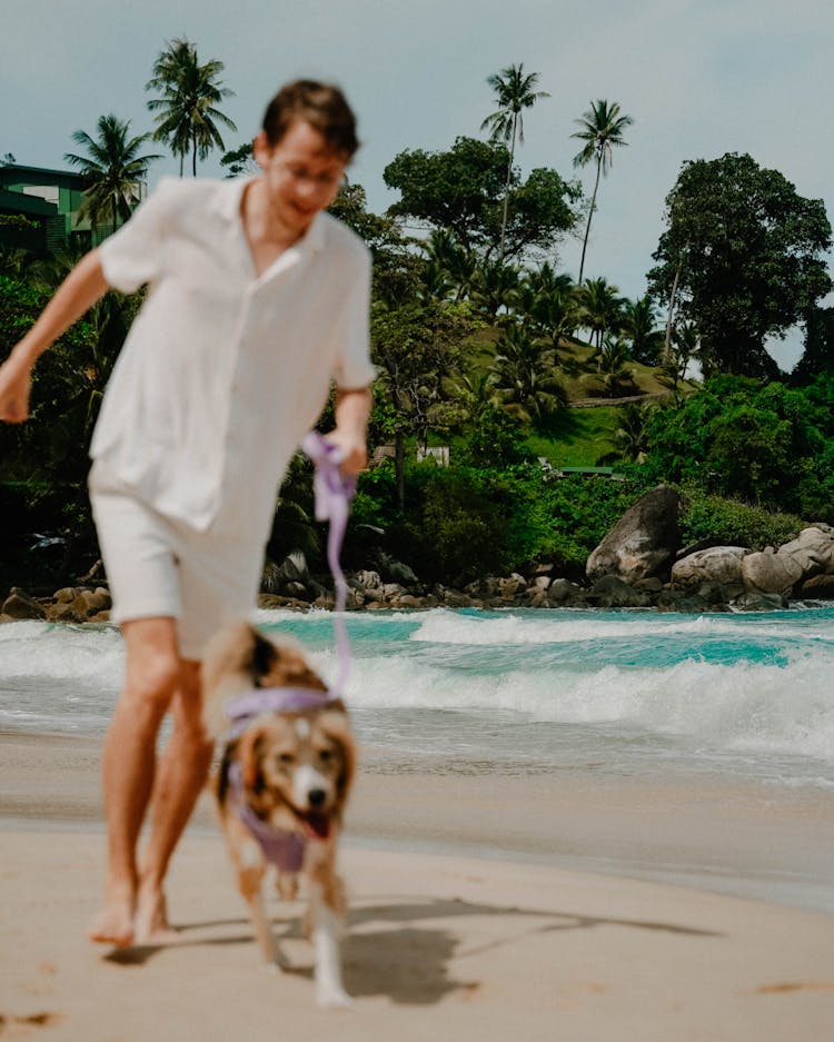 Man Running With His Dog On The Beach 