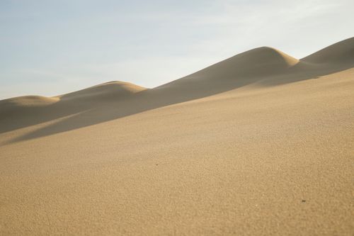 Free Golden sand dunes rolling under a clear blue sky in Quang Binh, Vietnam. Stock Photo