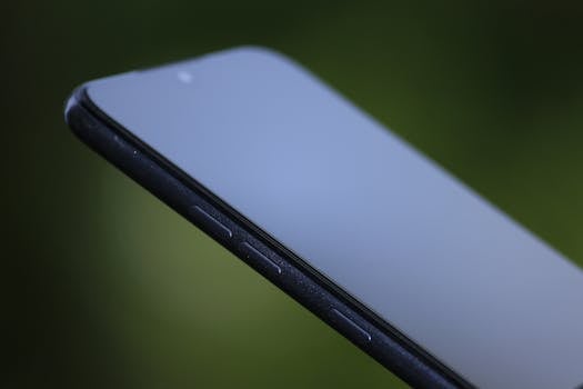 Close-up shot of a sleek black smartphone against a blurred green background, showcasing modern design.