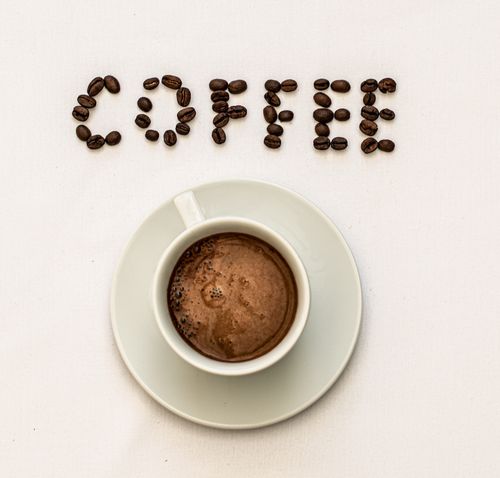 Free Top view of a coffee cup and beans spelling 'coffee' against a neutral background. Stock Photo