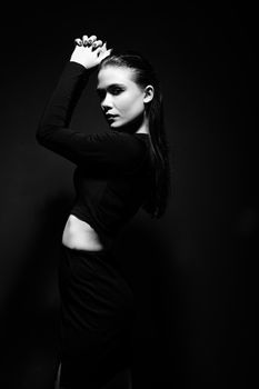 Artistic black and white portrait of a woman posing with hands on head.
