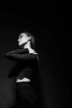 A striking black and white portrait of a woman posing with her hand on her shoulder.